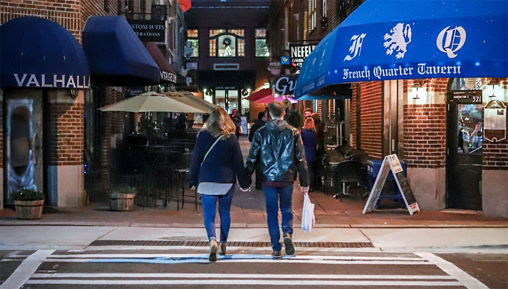 Couple walking on street near restaurants
